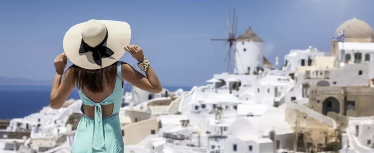 Woman looking at the beautiful village of Oia on the island of Santorini | International travel insurance