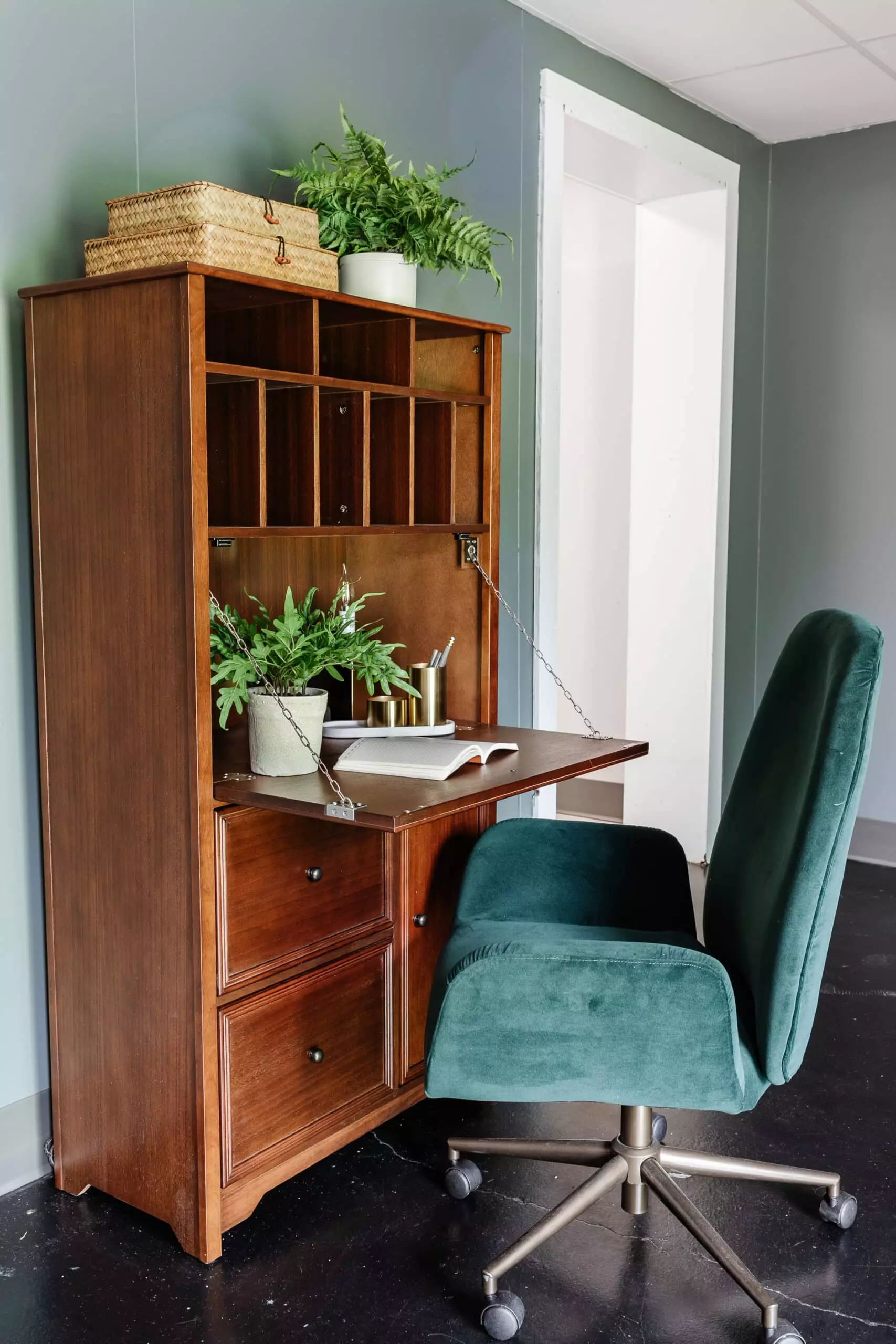 wooden secretary desk and green desk chair in an office