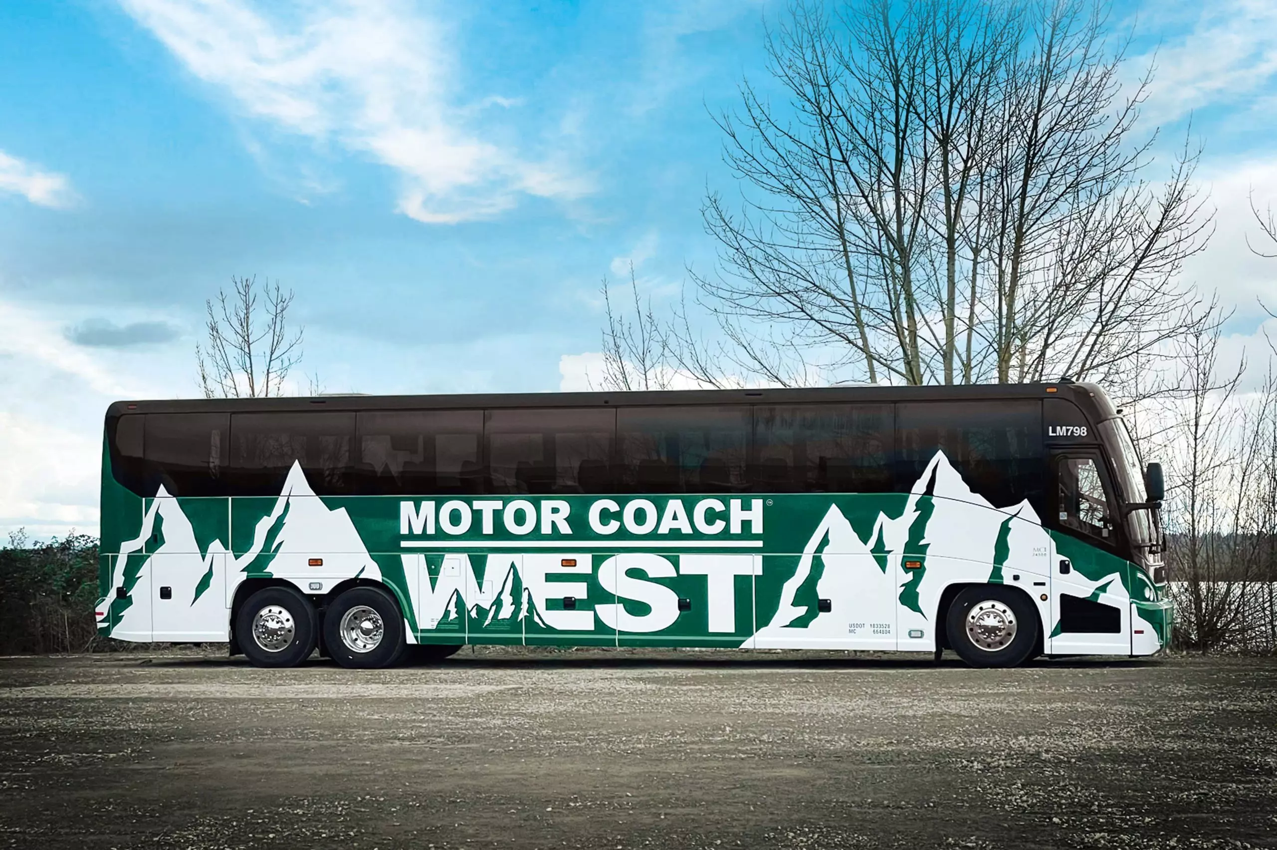 Green Motor Coach West bus against partly cloudy sky background